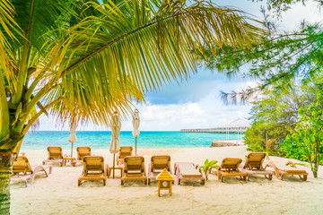 Beach chairs with umbrella at Maldives island, white sandy beach and sea .