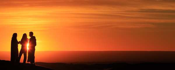 silhouette of men standing in the desert at sunset