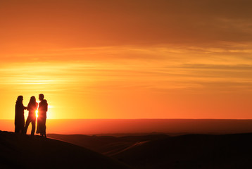 Fototapeta na wymiar silhouette of men standing in the desert at sunset