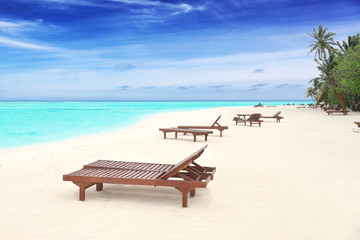 Fototapeta na wymiar Sun loungers on beach in summer day