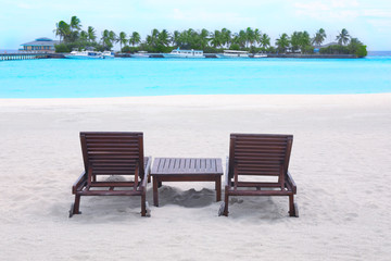 Fototapeta na wymiar Wooden sun loungers on beach at sea resort