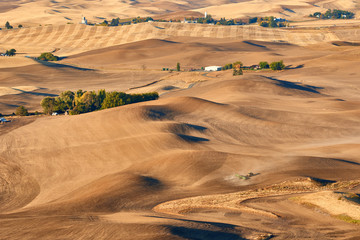 An aerial view of tractor plowing at sunrise. The Palouse Hills with farmland in autumn season.