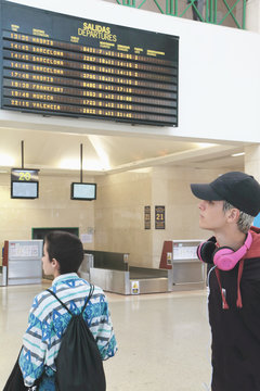 A boy and a girl at the airport consulting the next departures
