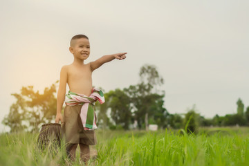 Asian boy to fish during the holidays in green farm field in summertime., Thailand.