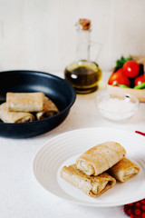 Hearty and delicious breakfast or lunch, thin pancakes filled with chicken with fresh vegetables, herbs and olive oil on a light background