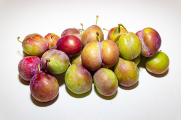 Unripe plums on white background