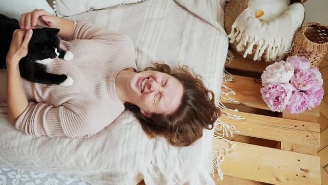 Woman stroking cat on bed