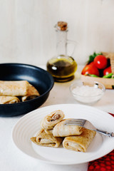 Hearty and delicious breakfast or lunch, thin pancakes filled with chicken with fresh vegetables, herbs and olive oil on a light background