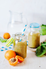 Healthy food, summer drinks, fruit and vegetable smoothie with banana, apricot and spinach in glass bottles on a light background, detox