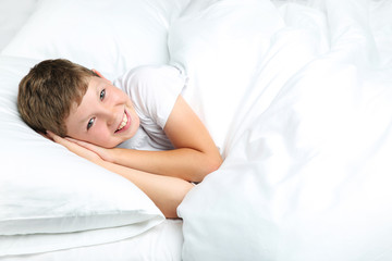 Young boy sleeping in white bed