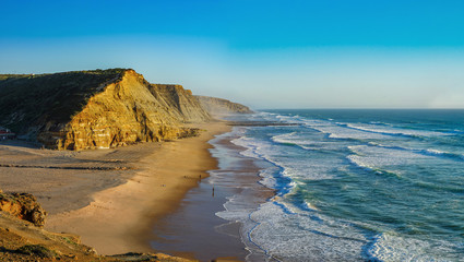 Yellow rocks and sand on portuguese coastline, vivid ocean water