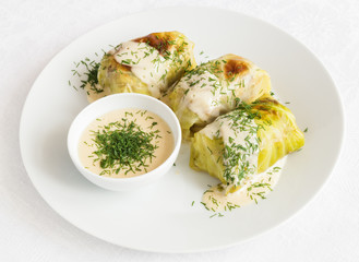 cabbage leafs stuffed with meat and rice filling served with broth based sauce and sprinkled with dill