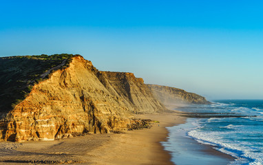 Fototapeta na wymiar Vivid yellow sand and rocks on coastline, Portugal
