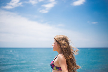 Naklejka premium A young blue girl stands out of arms, in the background of the sea, enjoys a holiday on the beach, and a sunburn