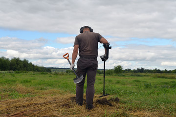 Digger with a metal detector in the field