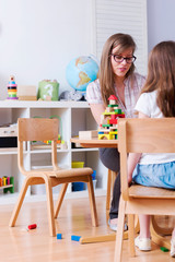 Preschool Teacher and Kid Playing with Wooden Building Blocks