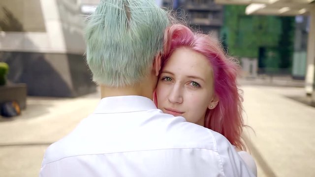 cute girl with green eyes and pink hair hugging her man with blue hair. they are modern free men