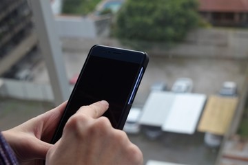Woman working sending a text message with her cellphone at a balcony