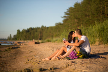 Fototapeta premium A young couple in love, on the shore of the Bay at sunset