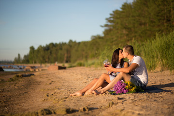 Fototapeta premium A young couple in love, on the shore of the Bay at sunset