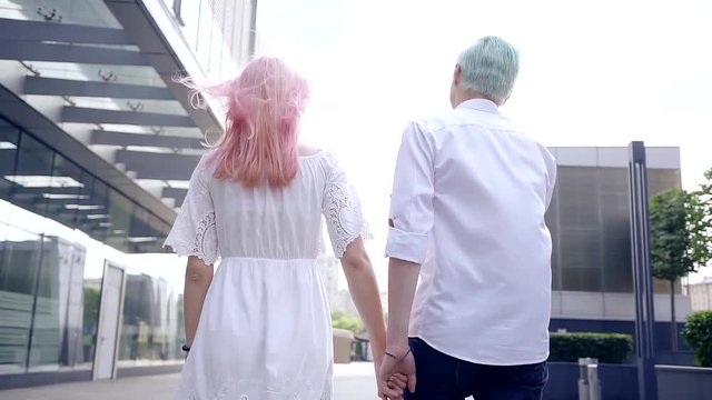 Young couple with colorful hair walk through city