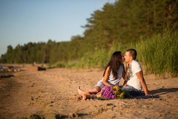 A young couple in love, on the shore of the Bay at sunset