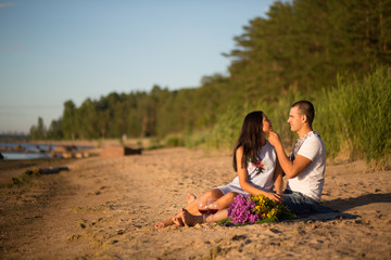 A young couple in love, on the shore of the Bay at sunset