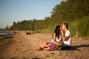 A young couple in love, on the shore of the Bay at sunset