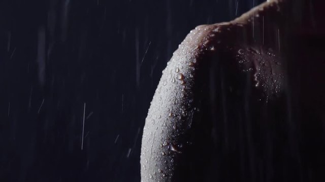 women's shoulder in the darkness under the water jets. drop broken delicate healthy skin. hand with long nails stroking his shoulder. dark room