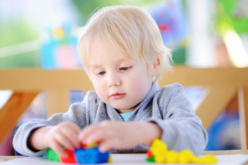 Creative boy playing with colorful modeling clay at kindergarten