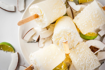 Summer desserts. Vegan diet food. Coconut and lime home fruit ice cream popsicles on a stick. On white marble table, copy space