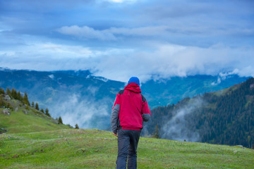 Traveler walks through the alpine meadow to the cliff