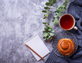 Feminine workspace with bun, cup of tea and notebook
