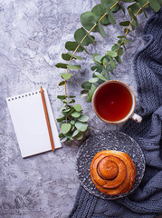 Feminine workspace with bun, cup of tea and notebook
