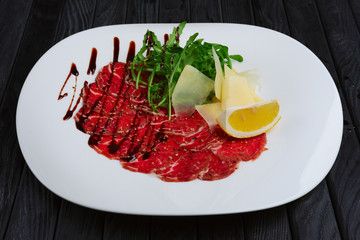 Beef carpaccio with cheese, white bread toasts and lemon