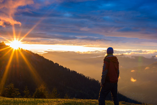 Lonely traveler stands in the mountains, during the sunset