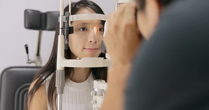 Woman looking at eye test machine in ophthalmologist