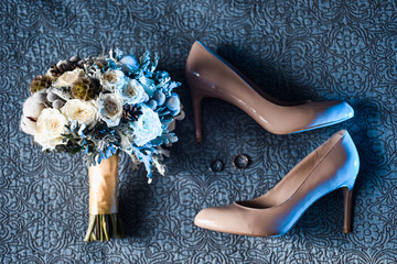 Couple close-up of engagement gold wedding rings on the background of an elegant bride's bouquet of flowers With shoes