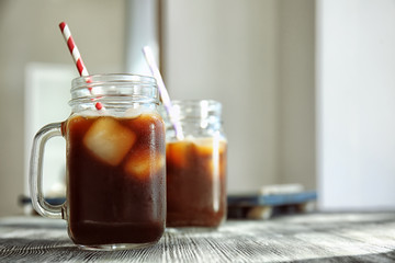 Mason jar with cold brew coffee and straw on wooden table