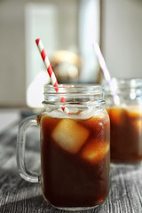 Mason jar with cold brew coffee and straw on wooden table
