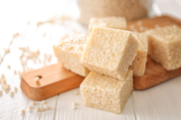Wooden cutting board with rice treats on white table