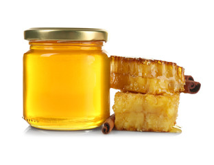 Jar with honey, honeycombs and cinnamon on white background