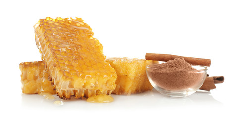Honeycombs, bowl with powder and cinnamon on white background