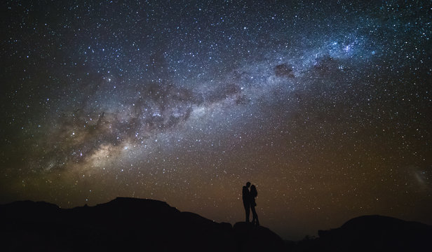 Landscape with Milky Way. Night sky with stars and silhouette of a couple kissing on the mountain.