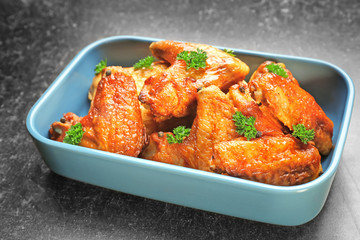 Dish with delicious chicken wings on kitchen table