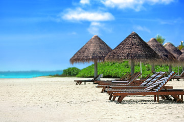 View of tropical beach with sun loungers on summer day