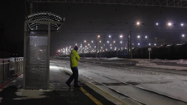 Train station master checks train and waves to driver to clear departure.