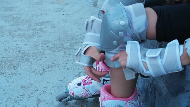 Legs of a child in roller skates. A little girl dresses protection for the rollers.