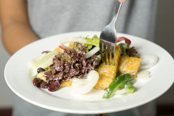 Woman mixing, cooking fresh salad and vegetable for making salad.