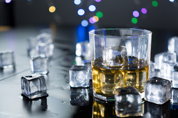 Close up whiskey in glass with ice cubes.dark black background.